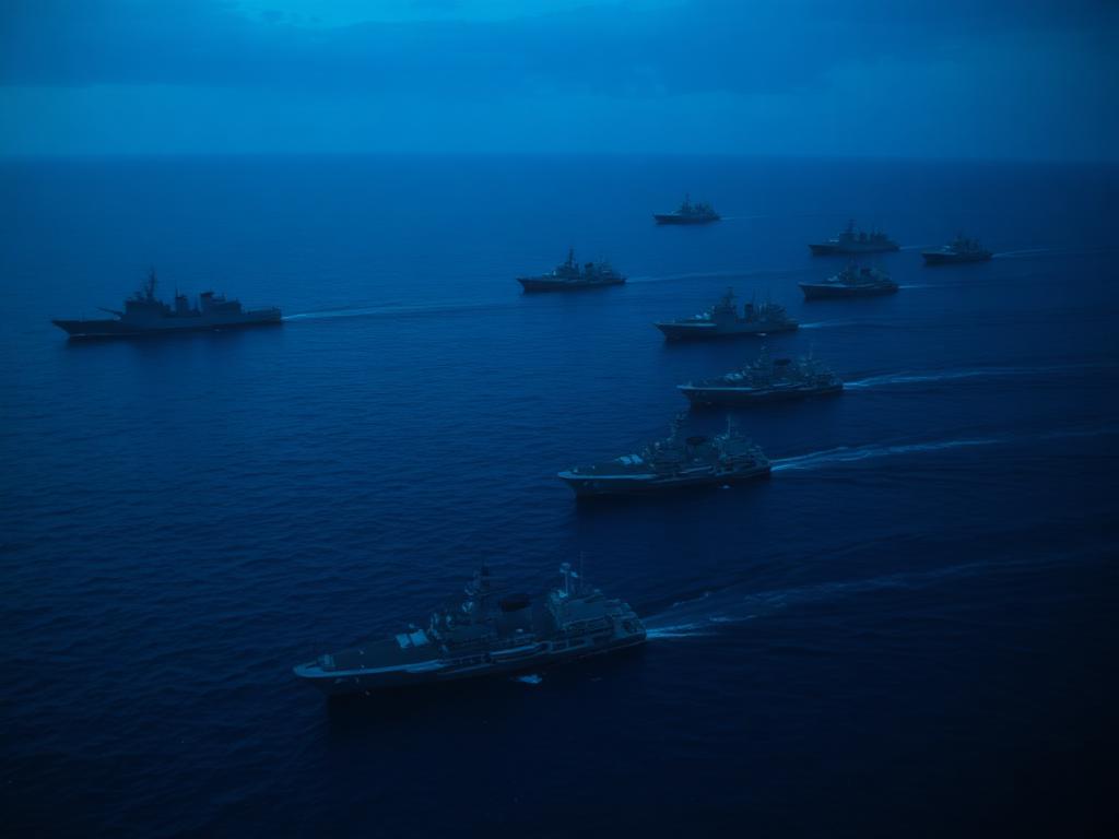 Naval vessels sailing in formation at blue hour, viewed from above
